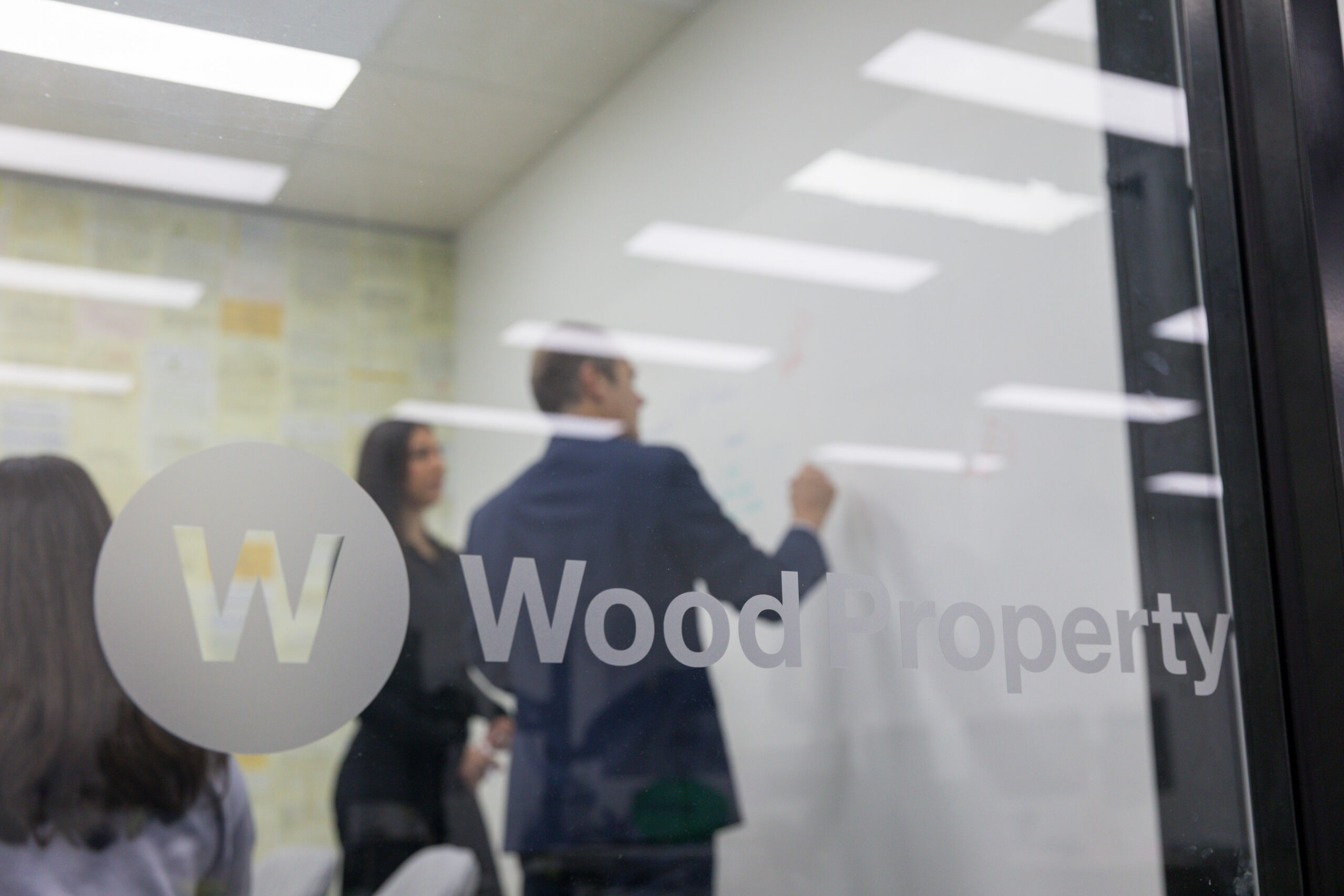 Wood Property team meeting viewed through the branded office window
